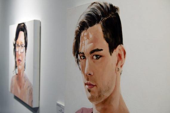 Two paintings, one of a man, his gaze directed toward the camera and the other of a woman